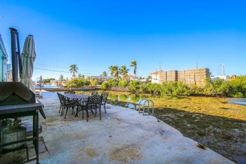 un patio con mesas y sillas junto a un cuerpo de agua en Fishermans Bungalow Hideaway, en Conch Key