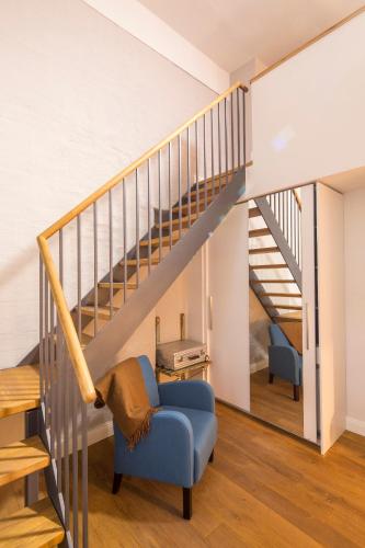 a living room with a blue chair and stairs at Hotel Oderberger in Berlin