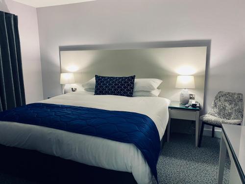 a bedroom with a large bed and a chair at Dean Park Hotel in Kirkcaldy