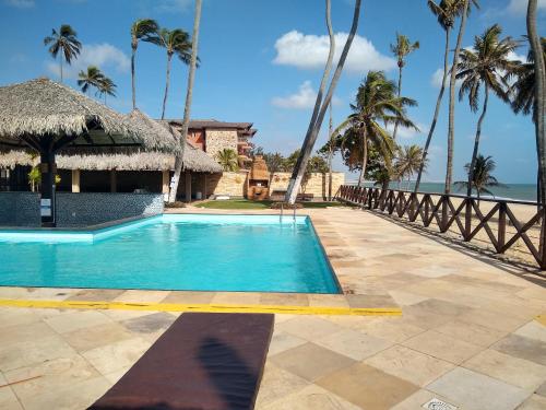 a swimming pool next to a resort with the ocean at Eco Paradise Temporada Aconchegante - Joana Vasconcelos in Cumbuco