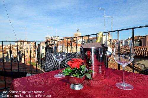 - une table avec deux verres à vin et une fleur sur le balcon dans l'établissement Charming Venice Apartments, à Venise