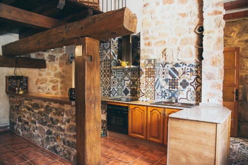 a kitchen with wooden cabinets and a stone wall at Casa Rural La Salitrosa in El Pedernoso