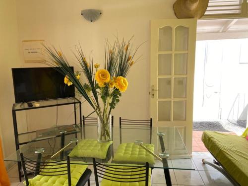 a glass table with a vase of yellow flowers on it at Villa Marine in Sainte-Anne
