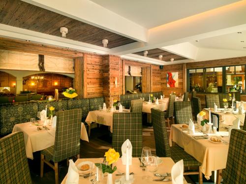 a restaurant with white tables and green chairs at Aktivhotel Alpendorf in Sankt Johann im Pongau