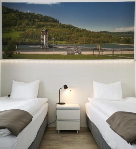 two beds in a white room with a window at Hotel Stronie in Stronie Śląskie