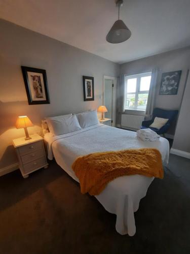 a bedroom with a large white bed and a window at Studio D in Doolin