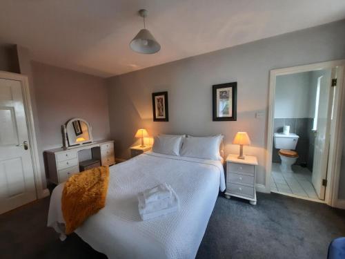 a bedroom with a large white bed and a bathroom at Studio D in Doolin