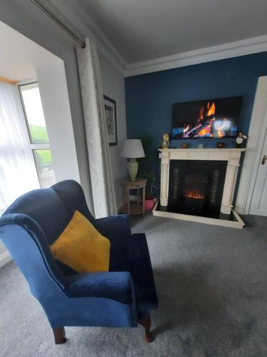 a living room with a blue chair and a fireplace at Studio D in Doolin