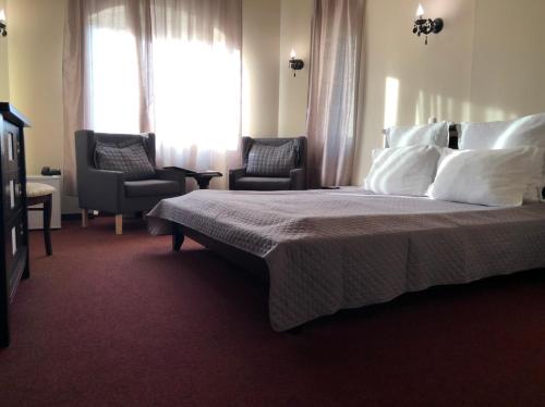 a bedroom with a bed and two chairs and a window at Hotel Imperial in Timişoara