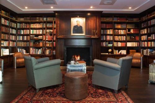 a library with two chairs and a fireplace at Støtvig Hotel in Moss