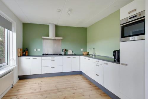 a kitchen with white cabinets and green walls at Vakantiewoning Seaewald in Zeewolde