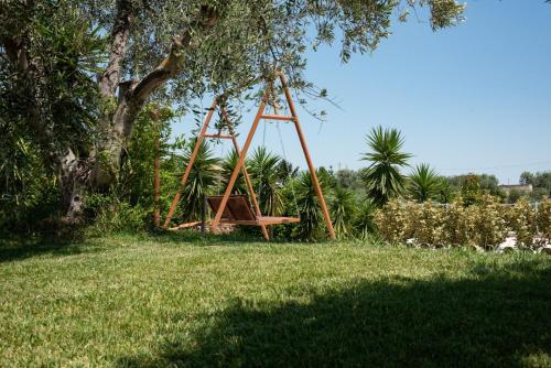 a swing set in a field under a tree at Agriturismo Macchia di Riso in Nova Siri Marina