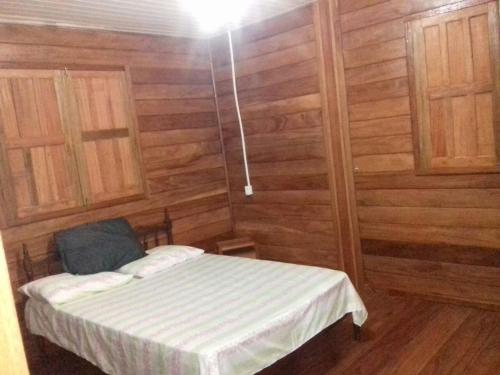 Kleines Zimmer mit einem Bett und Holzwänden in der Unterkunft Chalé Juquiri in Santarém