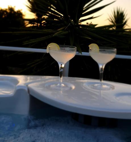 two martini glasses with a lemon on a plate at Agriturismo Macchia di Riso in Nova Siri Marina