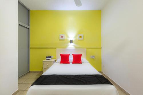 ein Schlafzimmer mit einem Bett mit zwei roten Kissen in der Unterkunft Capital O Oaxaca Guest Hotel in Oaxaca de Juárez