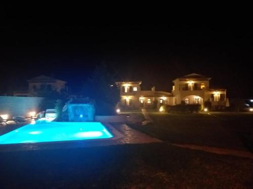 a swimming pool in front of a house at night at Stalakton Country Maisonettes in Halikounas