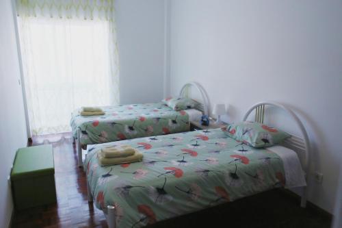 a bedroom with two beds and a window at apartamento na praia in Costa da Caparica