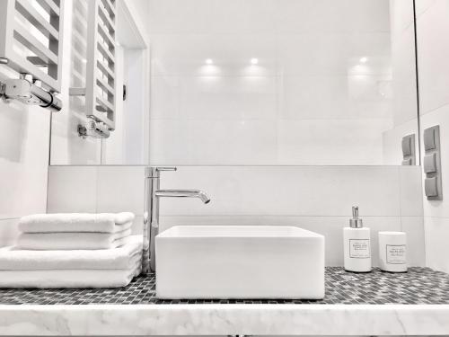 a white bathroom with a sink and towels on a counter at Luxury Apartments - Andersia Square Center & Półwiejska in Poznań