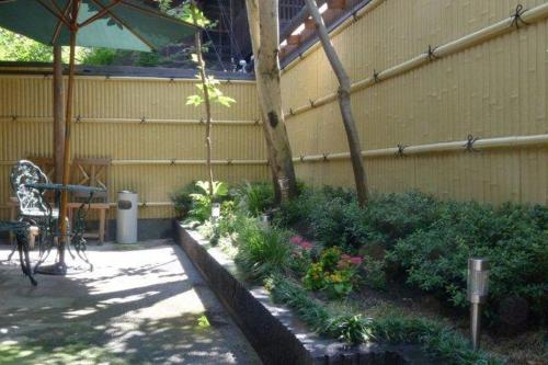 a garden with plants and a table and an umbrella at Machiya Kyoto Shogoin in Kyoto