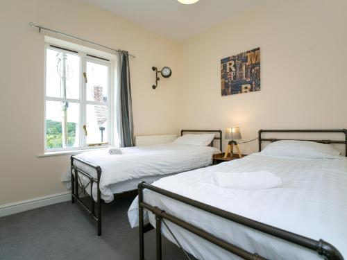 2 camas en una habitación con ventana en IRONBRIDGE - 18th CENTURY THREE BEDROOM COTTAGE - 6 BEDS en Ironbridge