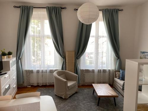 uma sala de estar com cortinas verdes e uma cadeira em Appartement großzügiges 2-Zimmer-Appartement im Zentrum von Potsdam direkt an der Havel em Potsdam