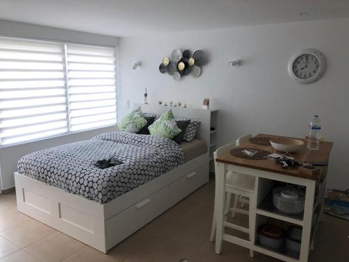 - une chambre avec un lit, une table et une horloge dans l'établissement Terrasses de Malmedy Studio 331-BOLY, à Malmedy