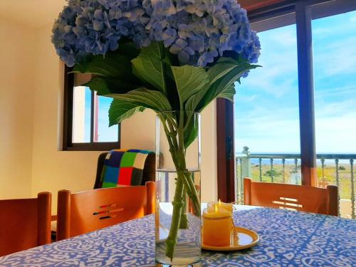 un jarrón lleno de flores azules sentado en una mesa en Apartamentos Ramona, en Lariño