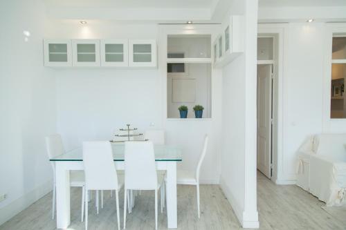 - une cuisine blanche avec une table à manger et des chaises blanches dans l'établissement FLH Madragoa Fresh Design Apartment, à Lisbonne