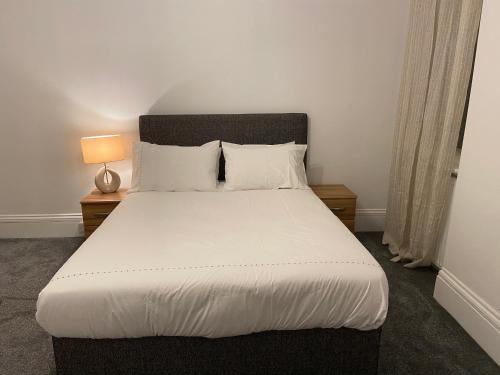 a bedroom with a bed with white sheets and a lamp at Charming Victoria Conversion Flat in Brentwood with a Garden & Free Parking in Brentwood