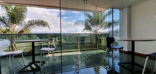 a room with glass walls and a table and chairs at Hotel Dubai in Manizales