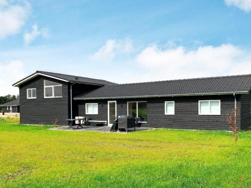 een zwart huis met een grasveld ervoor bij 10 person holiday home in Ansager in Ansager