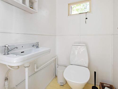 Baño blanco con aseo y lavamanos en Holiday home Væggerløse CXXXVI, en Bøtø By