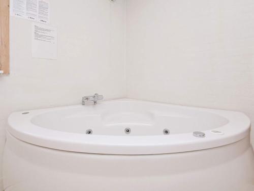 La salle de bains blanche est pourvue d'une baignoire blanche. dans l'établissement 16 person holiday home in Ulfborg, à Ulfborg