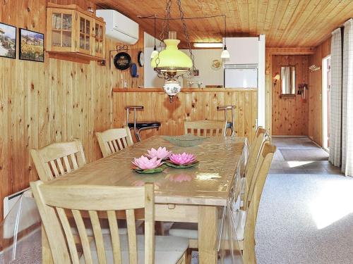 a dining room with a wooden table with flowers on it at 4 person holiday home in Hvide Sande in Bjerregård