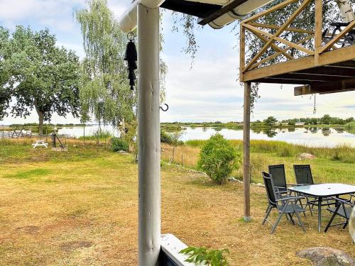 eine Veranda mit einem Tisch, Stühlen und einem See in der Unterkunft 5 person holiday home in S DER KRA in Söderåkra