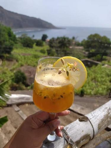 a person holding a glass with a lemon on it at Kaza Ladera in Seladinha
