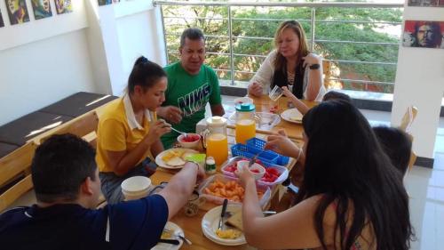 een groep mensen die rond een tafel zitten en eten bij Hostal Casa Roma in Taganga