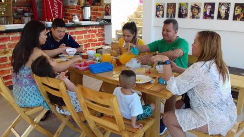 een groep mensen die rond een tafel zitten te eten bij Hostal Casa Roma in Taganga