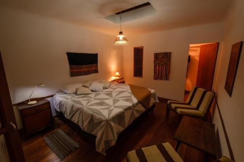 ein Schlafzimmer mit einem Bett und einem Stuhl in der Unterkunft Wasi in Sucre