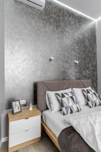 a bedroom with a bed with a concrete wall at InshiApartments on Popovycha str 2 in Lviv