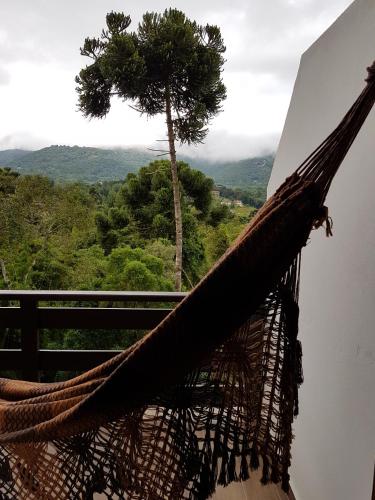 a hammock on a balcony with a tree in the background at Colline Verte in Monte Verde