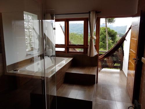 a bathroom with a glass shower and a window at Colline Verte in Monte Verde