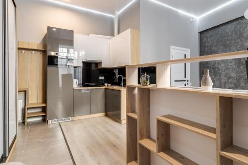 una cocina con electrodomésticos blancos y estanterías de madera en InshiApartments on Popovycha str 3, en Leópolis