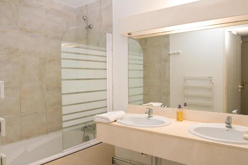 een badkamer met 2 wastafels en een spiegel bij Madame Vacances Residence Du Golf in Moliets-et-Maa