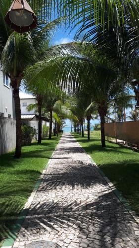 a path with palm trees on the side of a road at Guarajuba Porto Smeralda Village C02, térreo - GUARAJUBA TEMPORADA, viva mais de uma experiência de hospedagem conosco! 130m da praia in Guarajuba