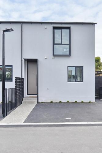 a white building with two windows and a door at Salisbury Style - Modern city apartment - Christchurch Holiday Homes in Christchurch
