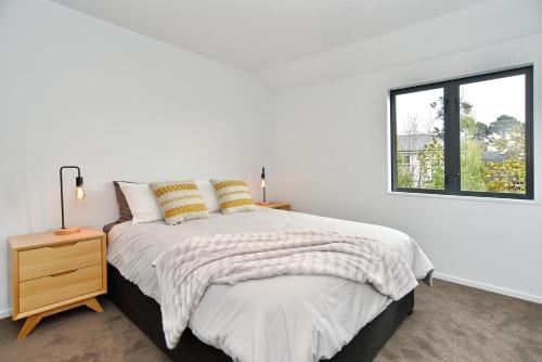 a white bedroom with a bed and a window at Salisbury Style - Modern city apartment - Christchurch Holiday Homes in Christchurch