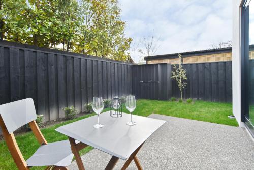 a white table with two wine glasses on it at Salisbury Style - Modern city apartment - Christchurch Holiday Homes in Christchurch
