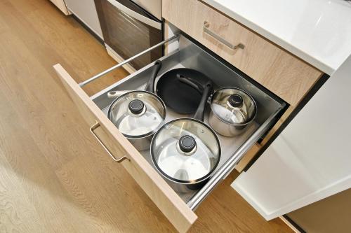 three metal pots in a drawer in a kitchen at Salisbury Style - Modern city apartment - Christchurch Holiday Homes in Christchurch