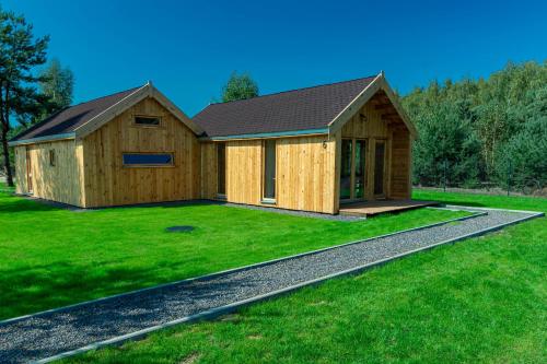 a large wooden building on a grass field at Leśna Osada przy Suntago Park in Krzyżówka